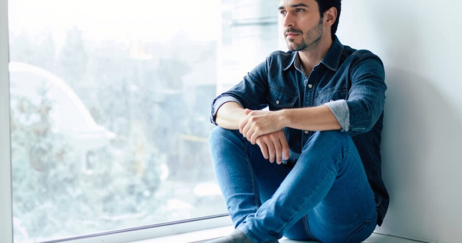 Hombre de 40 años reflexionando frente al espejo con mirada pensativa